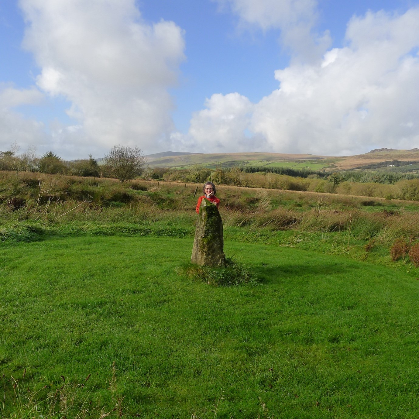 Alison Elliott looking overr a standing stone in a field