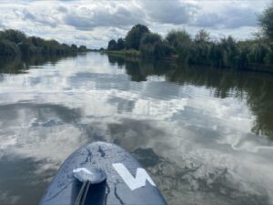 The nose of a paddleboard, with a view along a river