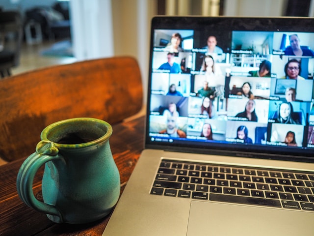 Online group on computer screen with coffee cup next to the laptop